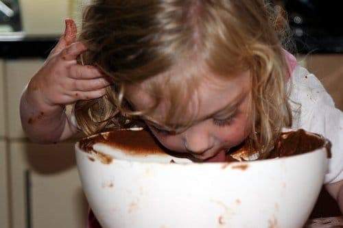 Un bambino che lecca il cioccolato rimasto nella ciotola